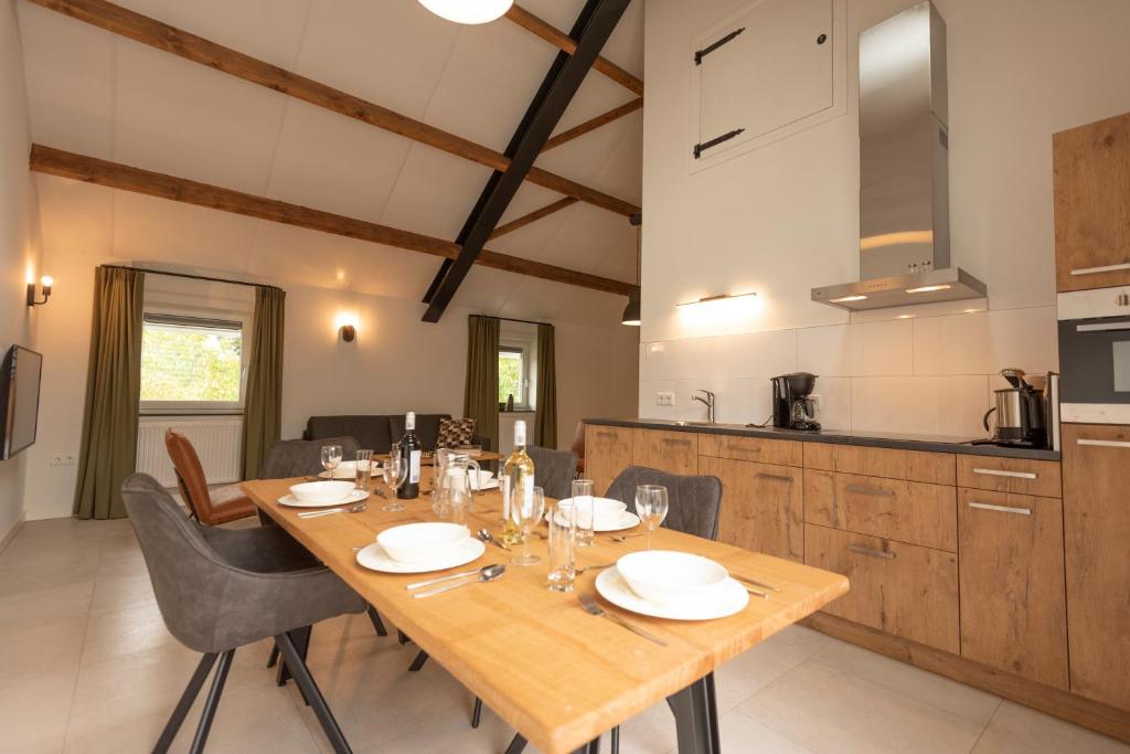 a dining room with a wooden table and a kitchen at Hoeve Kroonen in Schin op Geul