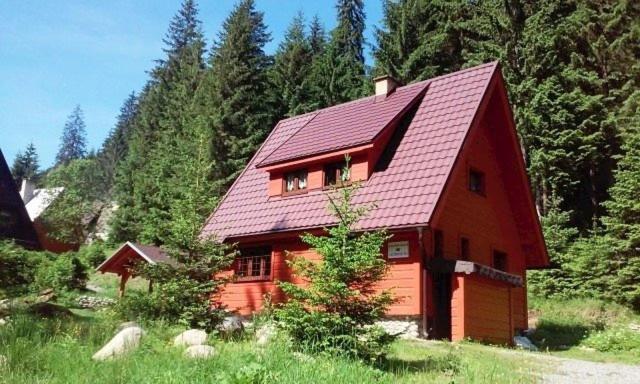 uma cabana vermelha no meio de uma floresta em Chata Ivan em Demanovska Dolina