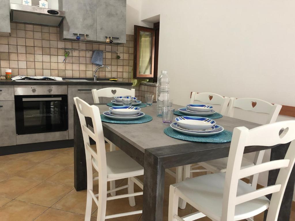 une cuisine avec une table en bois, des assiettes et des chaises dans l'établissement Casa Certosina, à Alghero