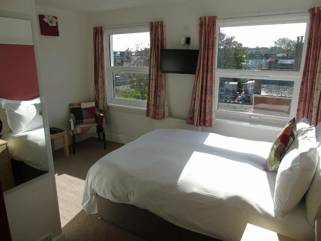 um quarto de hotel com uma cama e duas janelas em Carrington Guest House em Paignton