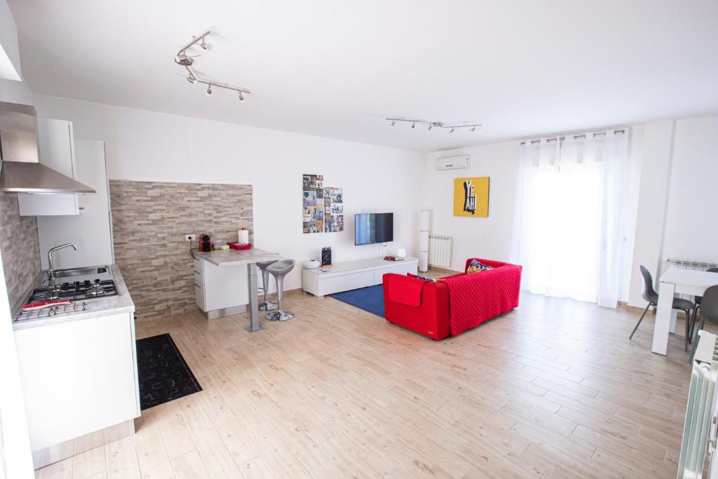 sala de estar con sofá rojo y cocina en Valmontone Travel House, en Valmontone
