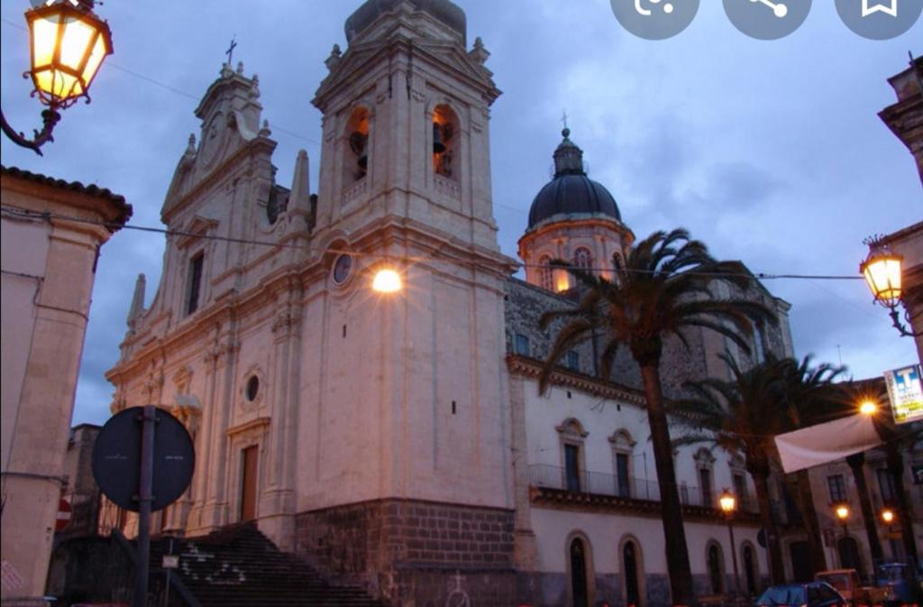 a building with a clock tower on the side of it at Casa Vacanze San Nicolò in Militello in Val di Catania