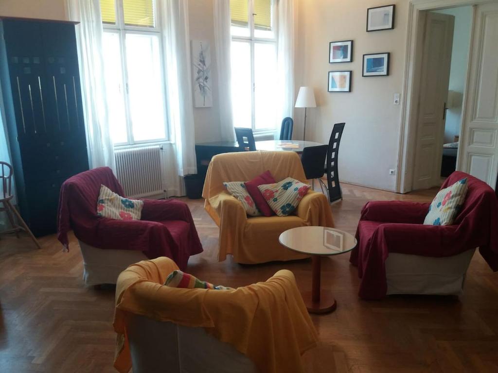 een woonkamer met banken, een tafel en ramen bij Geräumige zentrumsnahe Altbauwohnung in Wenen