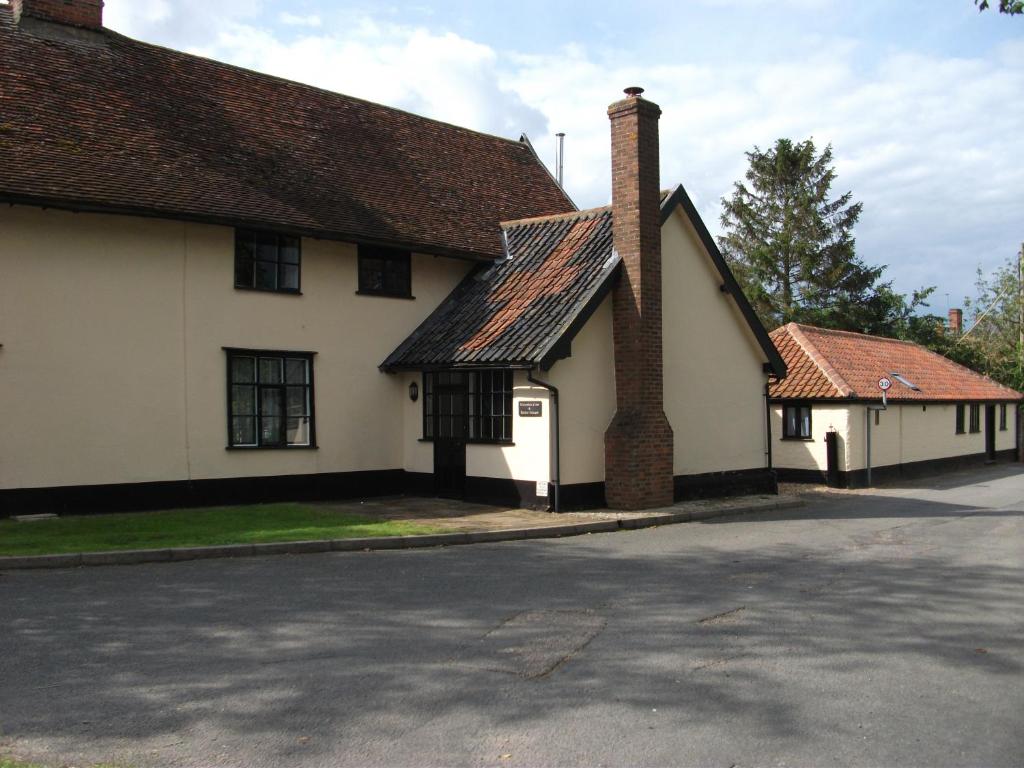 ein altes weißes Gebäude mit einem gemauerten Kamin auf einer Straße in der Unterkunft Withersdale Cross Cottages in Mendham