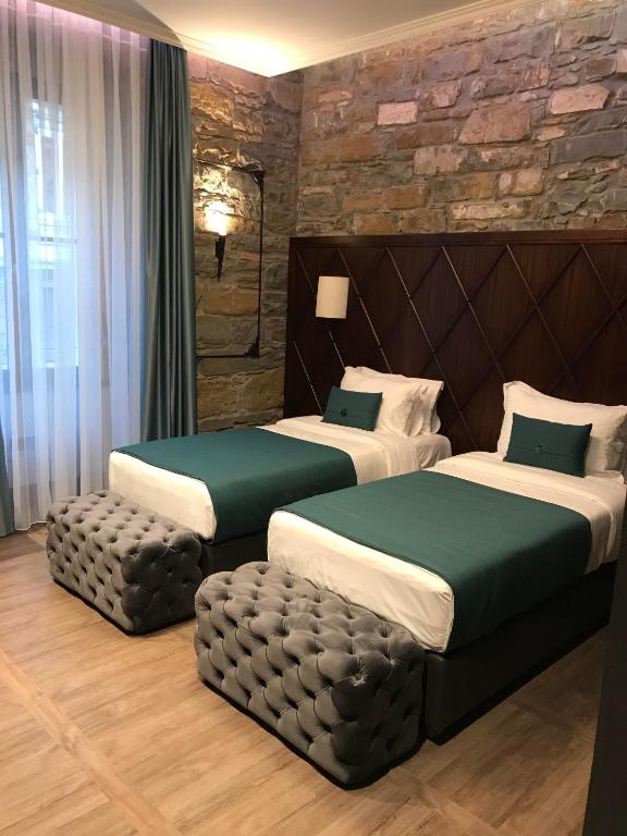 a hotel room with two beds and a stone wall at Hotel Solun in Trieste