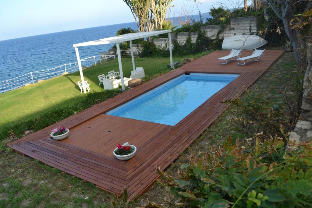 a swimming pool on a deck next to the water at Villa Sciammaca in Brucoli