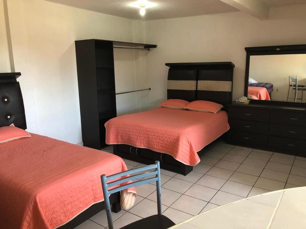 1 dormitorio con 2 camas, espejo y silla en HOTEL LAS FUENTES, en Tepotzotlán