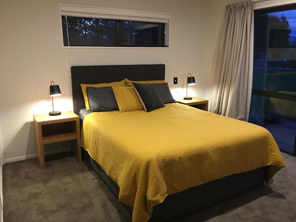 a bedroom with a large yellow bed with two lamps at Sandy Acre in North Loburn