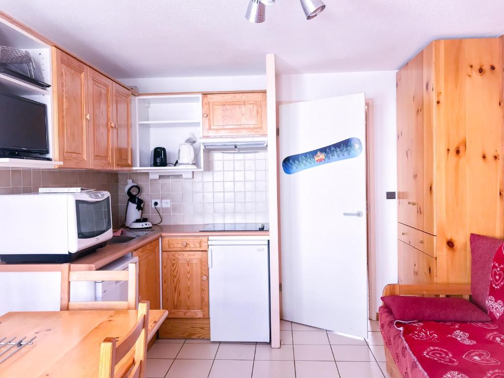 eine Küche mit Holzschränken und einem weißen Kühlschrank in der Unterkunft Boost Your Immo Les Deux Alpes 149 / Grande Chaume in Les Deux Alpes