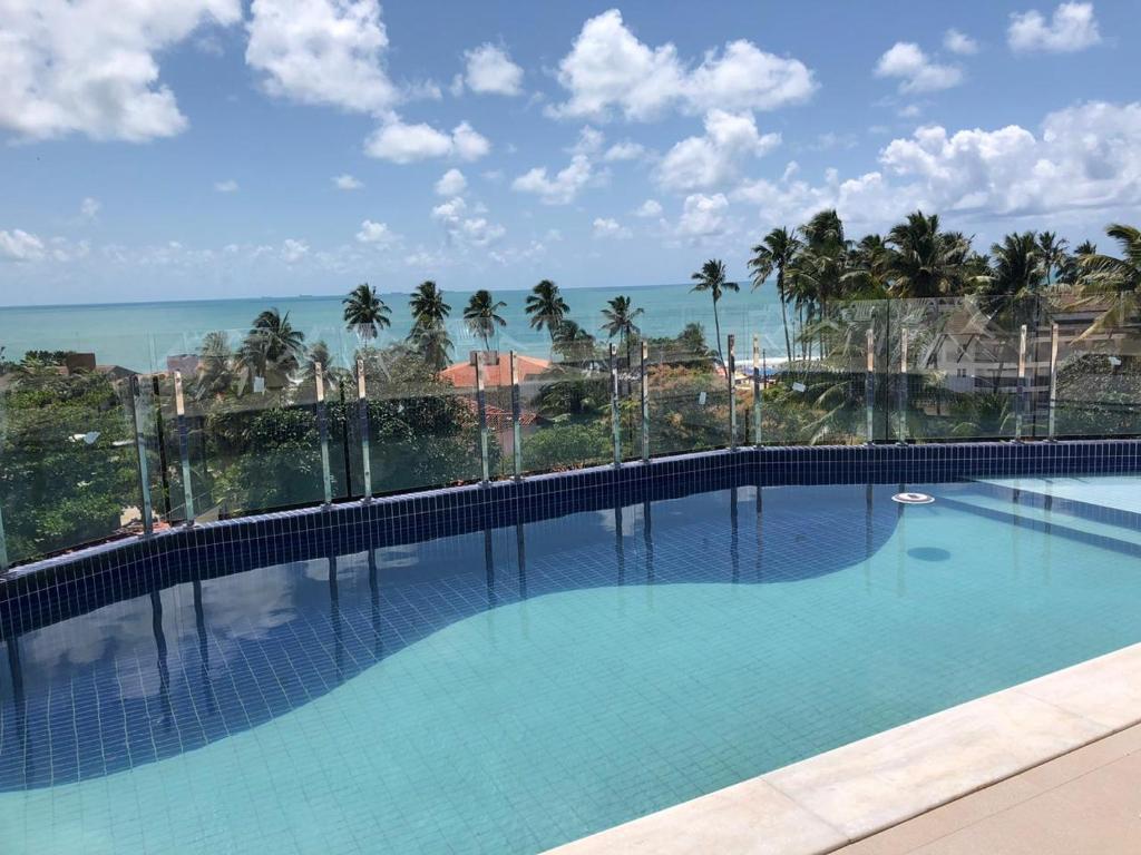 a large swimming pool with a view of the ocean at Makaiba Residence Flat dr Artur Licio in Porto De Galinhas