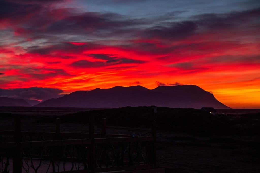 una puesta de sol en el desierto con montañas en el fondo en Stundarfriður cottages en Stykkishólmur