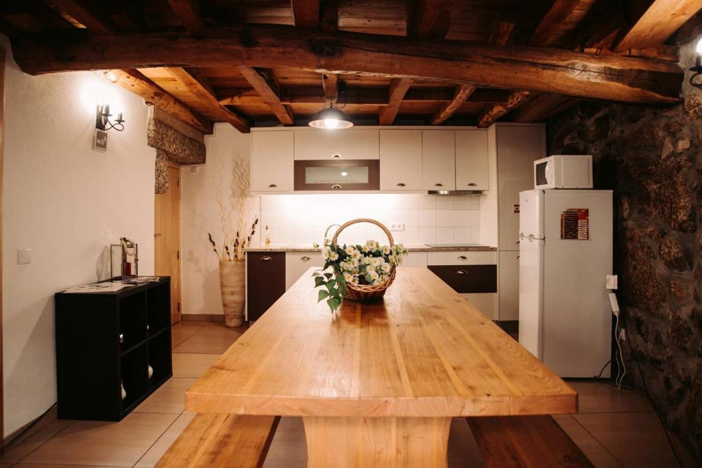 a kitchen with a wooden table and a refrigerator at Casa Ferreira in Sabugueiro