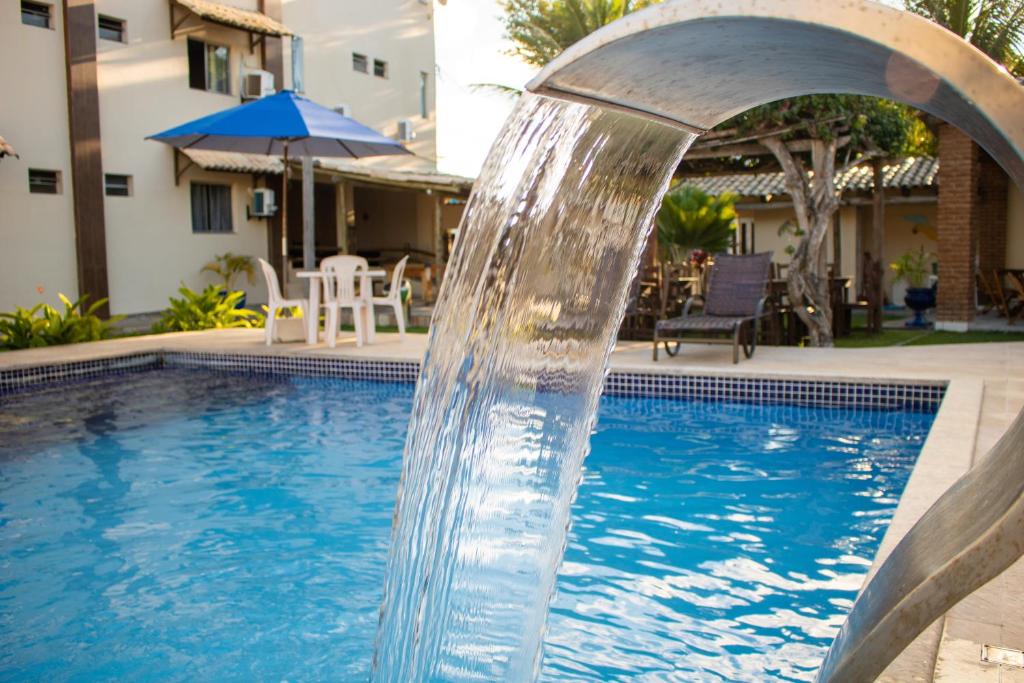 a swimming pool with a water fountain at Hotel Amendoeiras in Prado