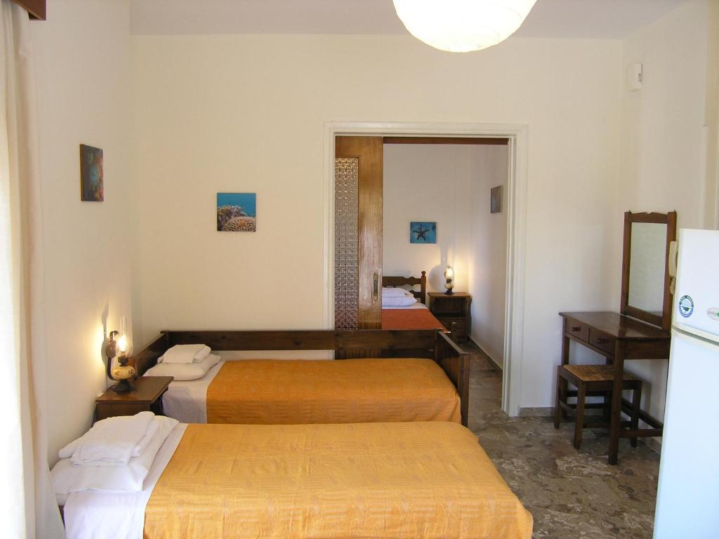 Habitación de hotel con 3 camas y espejo en Popy Apartments, en Ierápetra