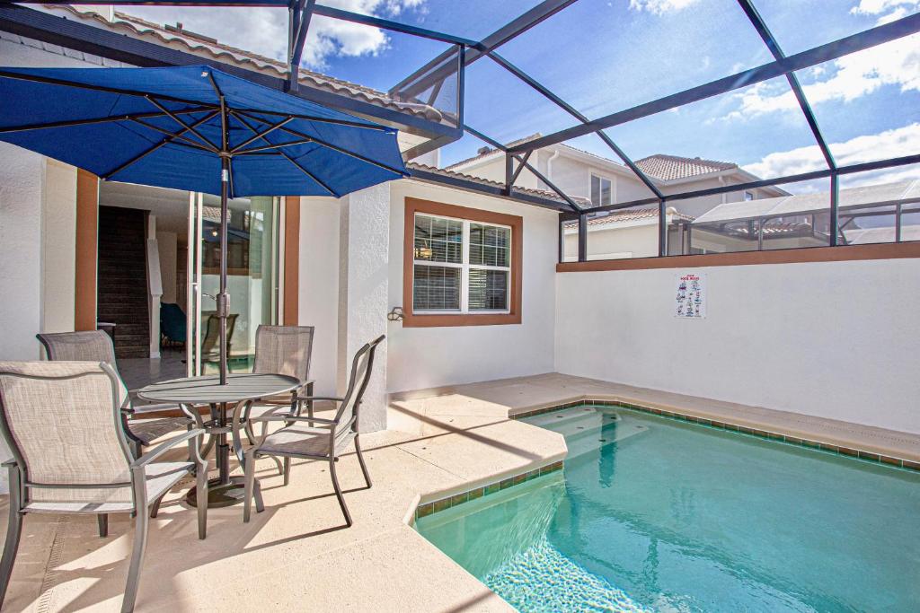 uma piscina com uma mesa e cadeiras e um guarda-sol em Marvelous 5 Bedroom w/ Pool Close to Disney 4811 em Kissimmee