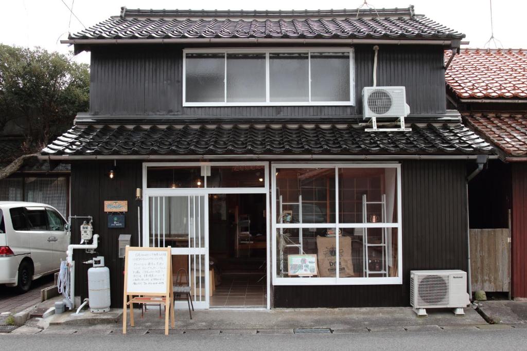 Ein schwarzes Gebäude mit einem Schild davor. in der Unterkunft Little Bird Inn 旧Minato Guesthouse in Sakaiminato