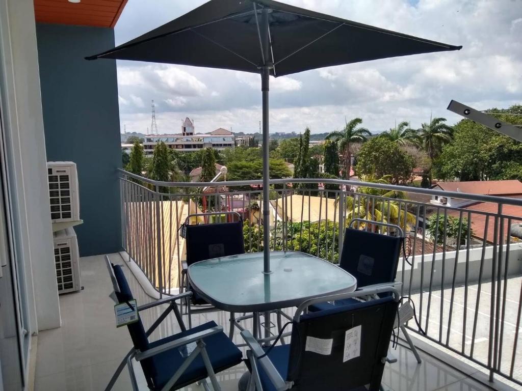 una mesa y sillas en un balcón con sombrilla en Premier Executive Apartment - The Ivy, East Legon en Accra