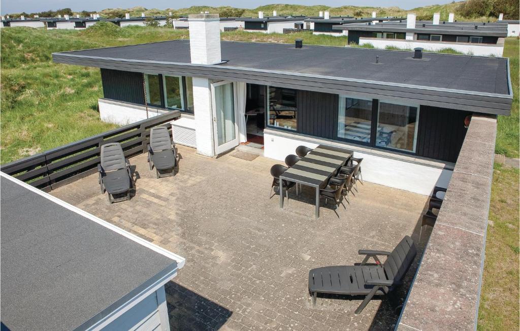 eine Terrasse mit Stühlen und Tischen auf einem Haus in der Unterkunft 2 Bedroom Beautiful Home In Pandrup in Rødhus