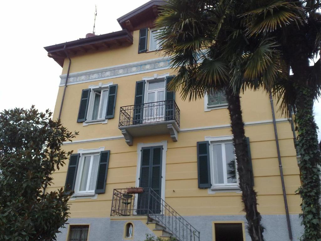 un edificio amarillo con ventanas negras y una palmera en Villa Stefy en Dervio