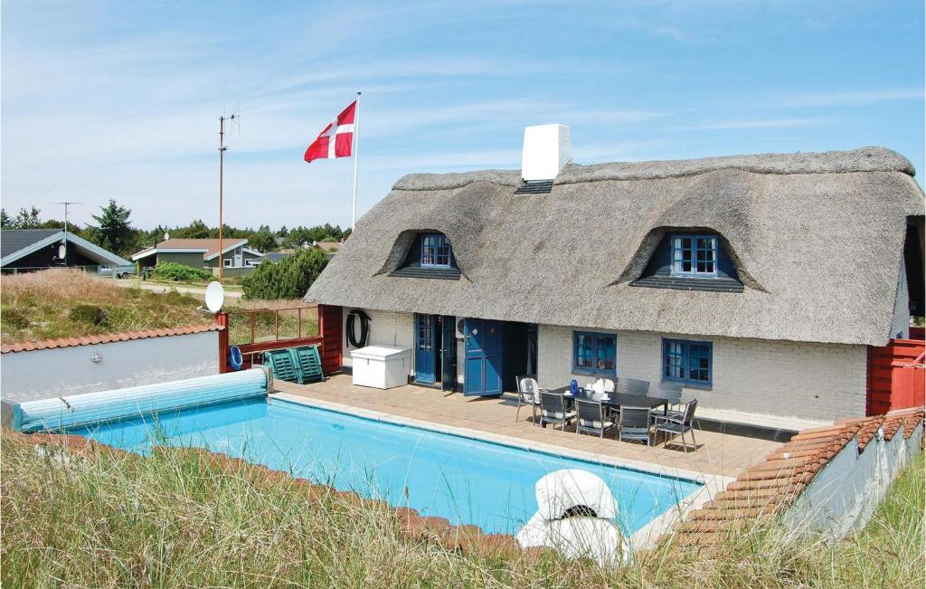 una casa con techo de paja junto a una piscina en Holiday Home Bjerregårdsvej Ix, en Bjerregård