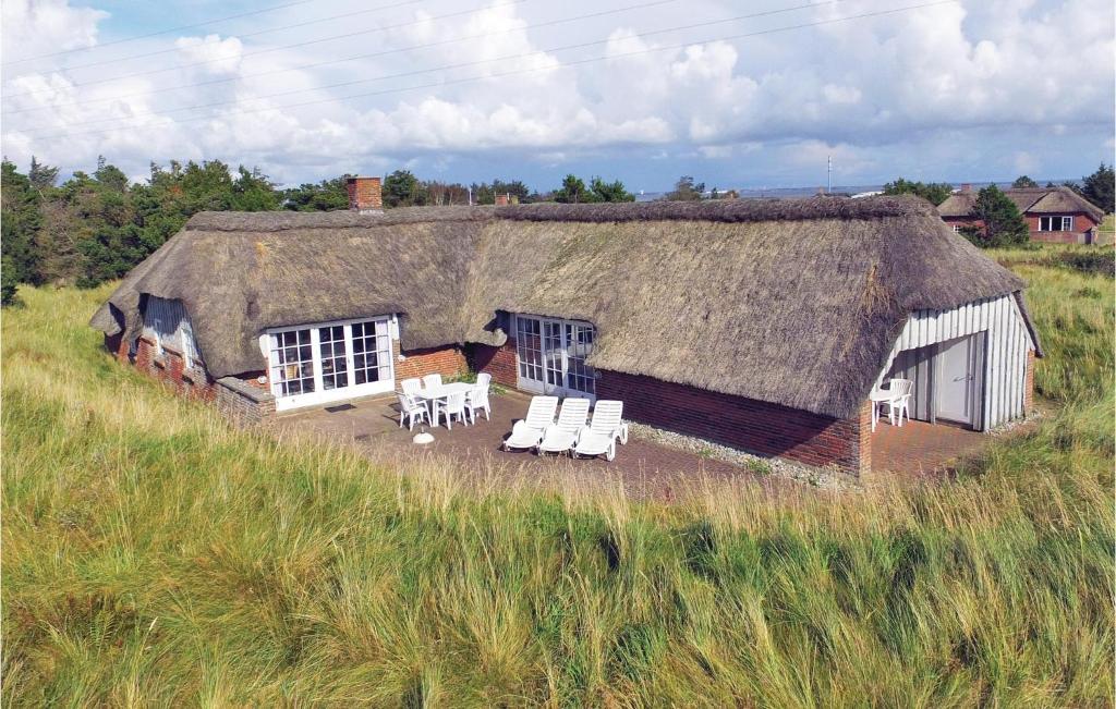 ein altes Haus mit einem Strohdach und weißen Stühlen in der Unterkunft Awesome Home In Ringkøbing With Kitchen in Klegod