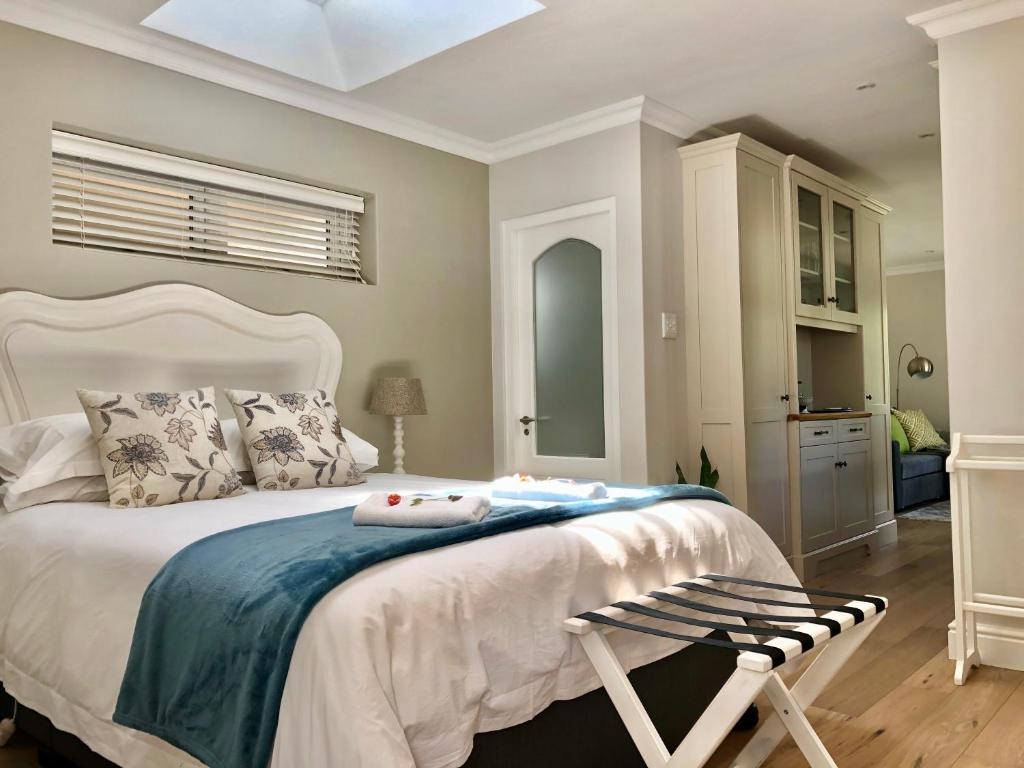 a bedroom with a white bed with a chair and a window at Garden Cottage - Leafy Constantia Guest House in Cape Town