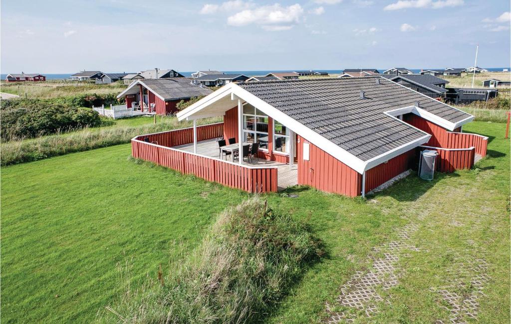 a red house with a gray roof on a grass field at Three-Bedroom Holiday Home In Hjorring in Hjørring