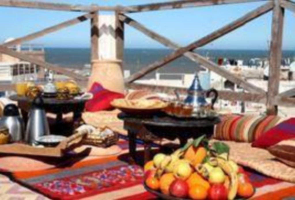 una mesa con comida y vistas a la playa en Riad Jade Mogador, en Essaouira