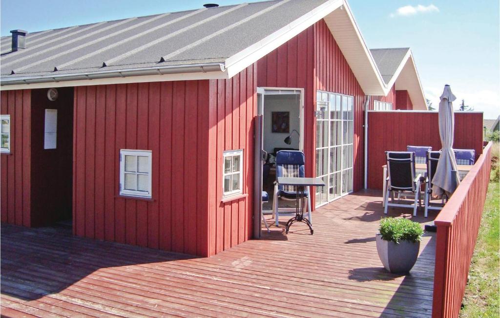 un edificio rojo con una terraza con sillas. en Gorgeous Home In Hvide Sande With Kitchen, en Nørre Lyngvig