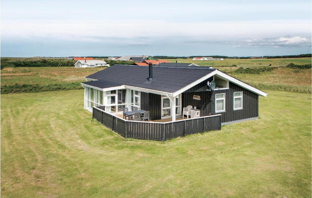una pequeña casa negra en un gran campo de hierba en 4 Bedroom Beautiful Home In Lkken en Løkken