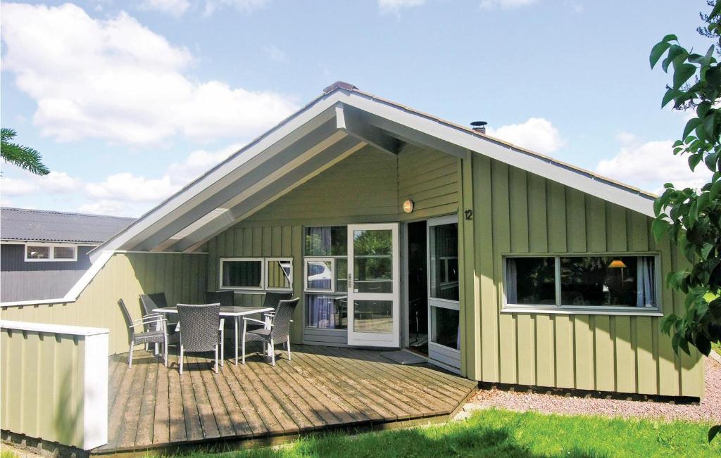 een groen huis met een terras met een tafel en stoelen bij Nice Home In Kirke Hyllinge With Wifi in Kirke-Hyllinge