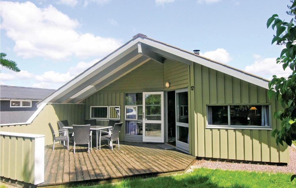 a green house with a deck with a table and chairs at Nice Home In Kirke Hyllinge With Wifi in Kirke-Hyllinge