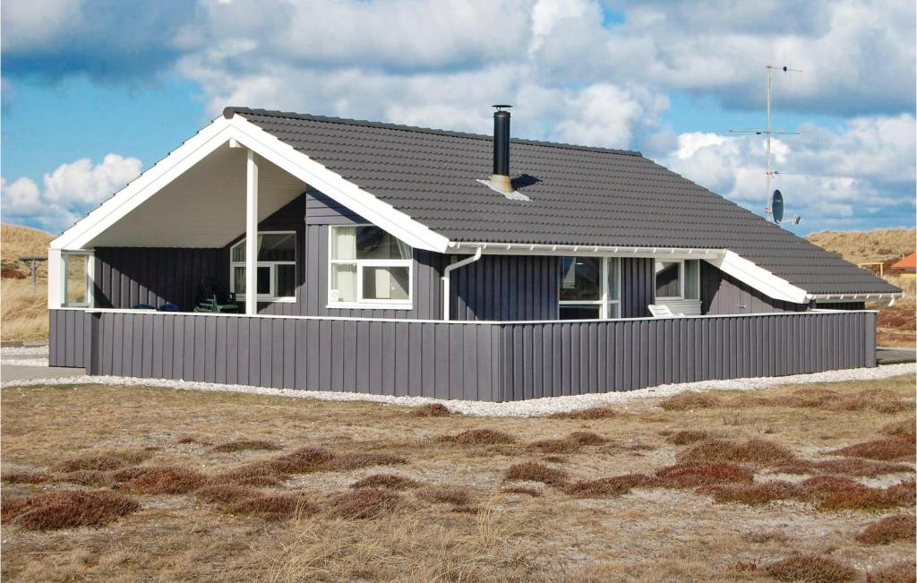 a house with a gray roof on top of a field at Holiday Home Bjerregårdsvej Denm in Bjerregård