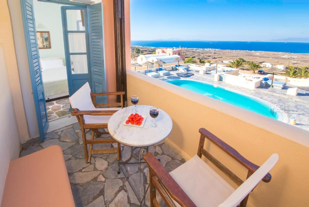 a balcony with a table and chairs and a pool at Anemoessa Villa in Oia