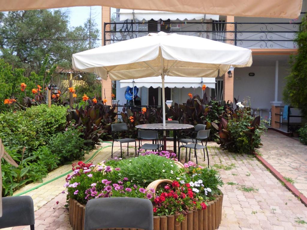 a patio with a table and chairs and flowers at Kostas Apartments & studios in Agios Georgios Pagon