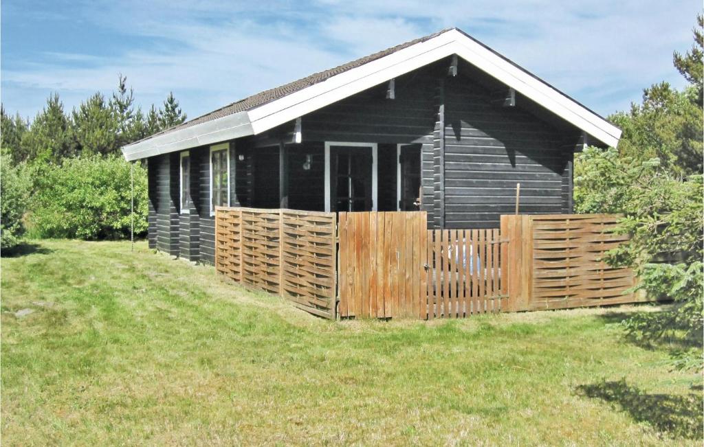 una cabaña negra con una valla de madera en un campo en Sandkassen, en Lønne Hede