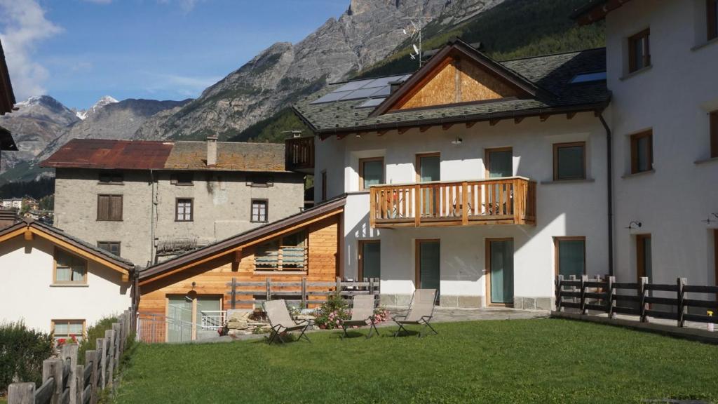 a house with a deck and a balcony with mountains at Chalet dei Reparti Bormio in Bormio