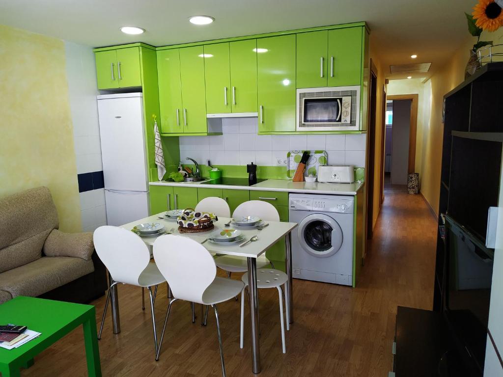 una cocina con armarios verdes, mesa y sillas en Arribes la corredera 3, en Aldeadávila de la Ribera
