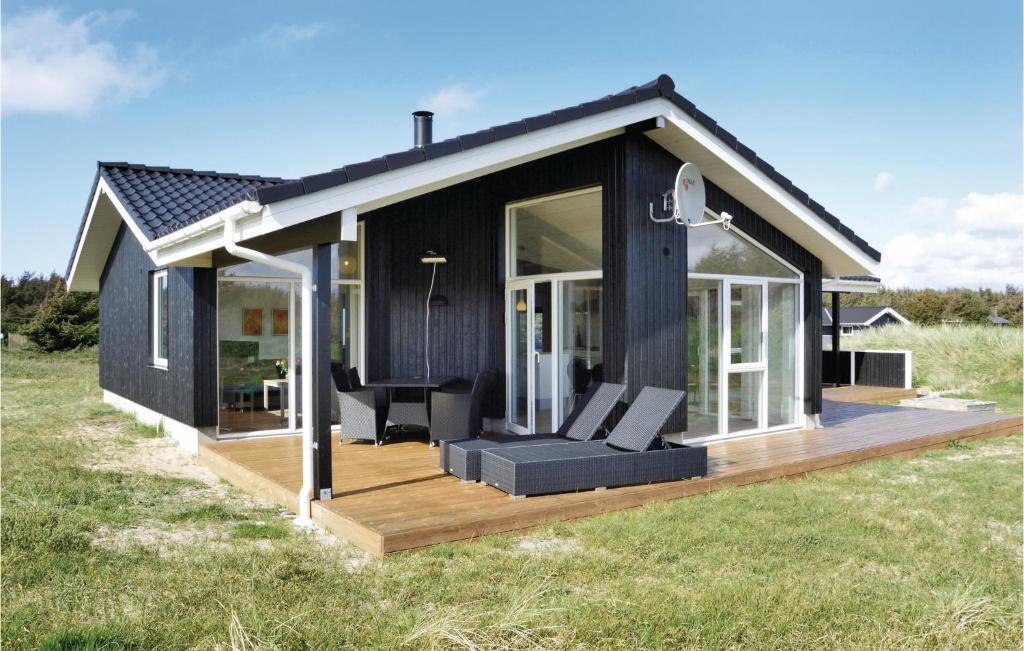 a black house with a deck with a couch at Holiday Home Lyngvejen X in Klegod