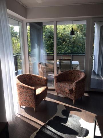 sala de estar con 2 sillas y ventanas grandes en Thermal Forest Apartment en Kiskunhalas