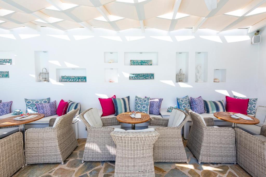 a restaurant with wicker chairs and tables with colorful pillows at Stelia Mare Boutique Hotel in Naousa