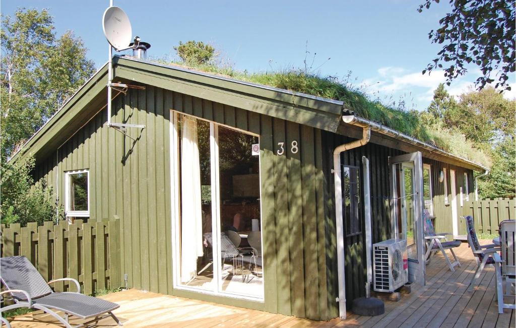 ein grünes Gebäude mit einer Terrasse mit Stühlen in der Unterkunft 3 Bedroom Stunning Home In Pandrup in Rødhus