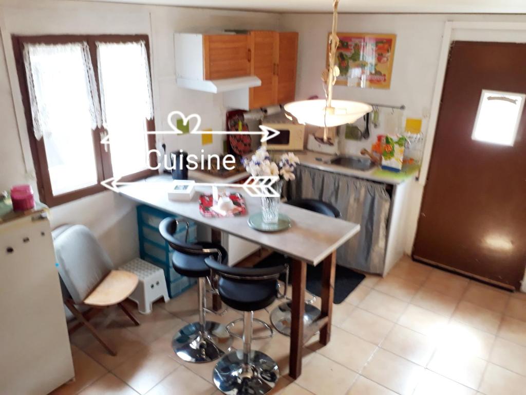 a kitchen with a table and some chairs in it at La Désirade in Montmirail