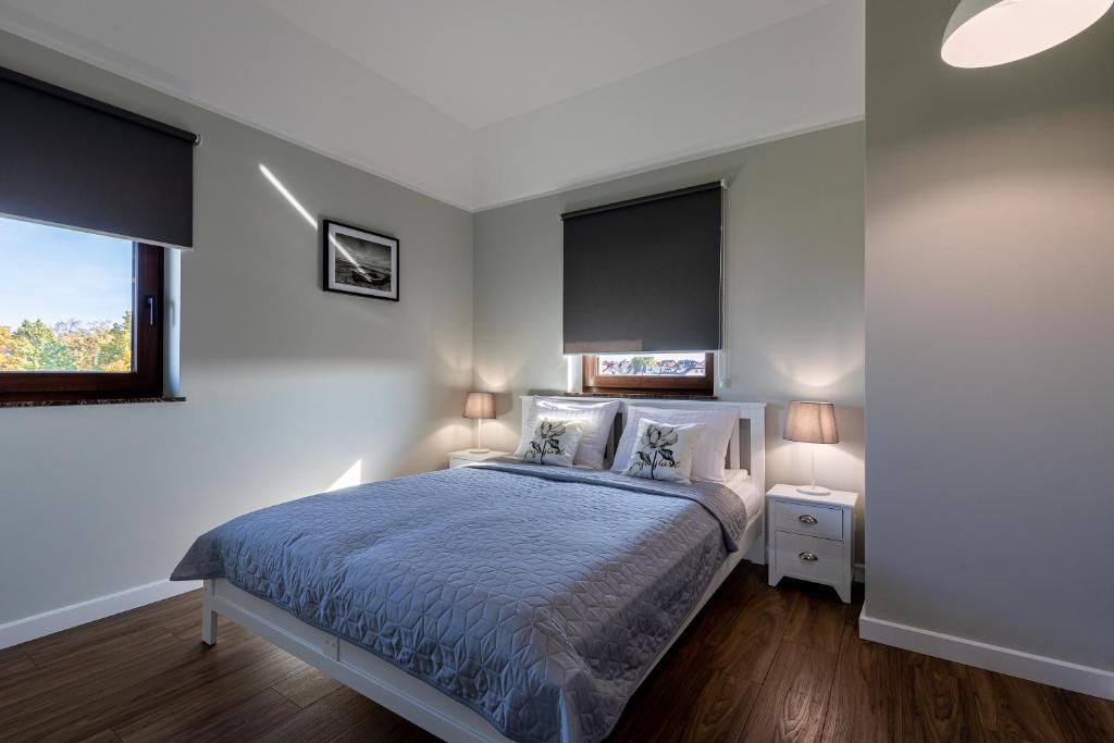 a bedroom with a bed with a blue comforter and two windows at Amare Apartments A2 in Mosty