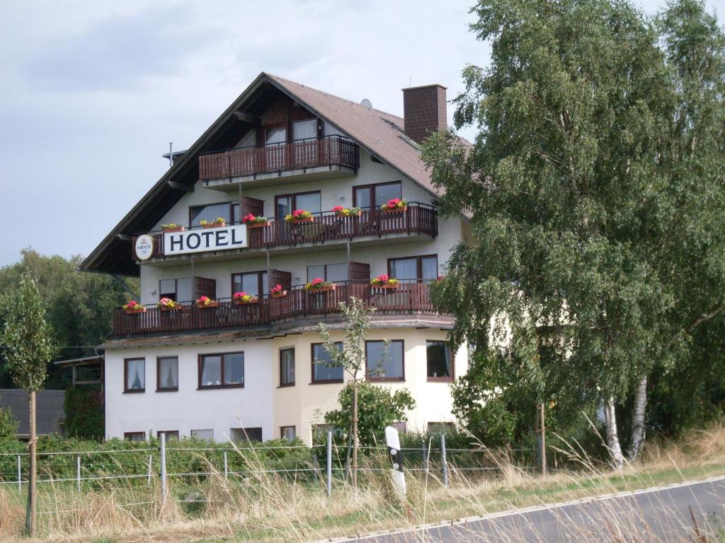 a hotel building with a balcony with flowers on it at Hotel Wildenburger Hof in Kempfeld