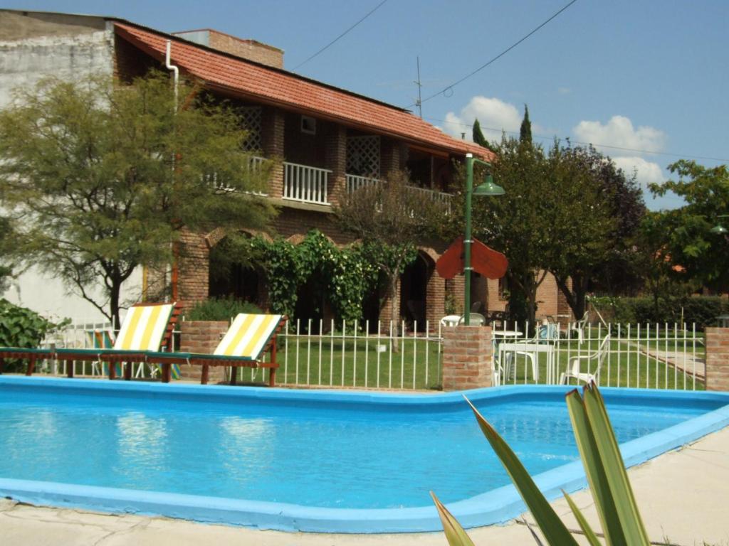 a swimming pool with chairs and a house in the background at Hosteria de la Villa ** in Villa Cura Brochero