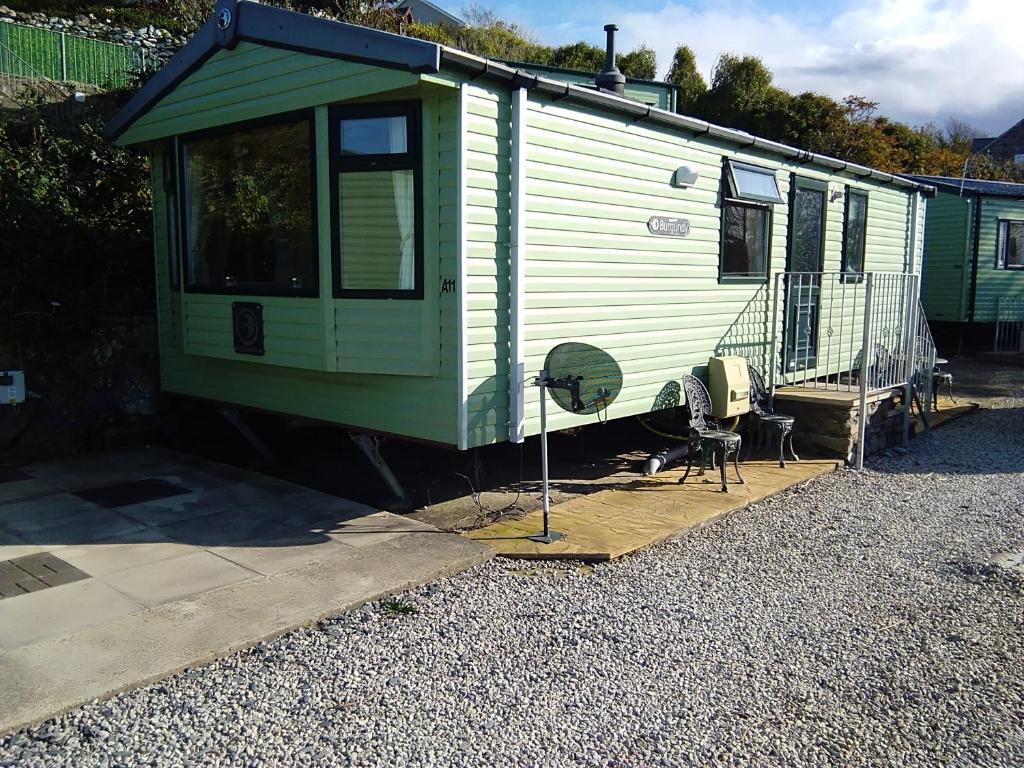 een groene trailer met een stoel en een ventilator bij A11 Hendre Coed Isaf static caravan in Barmouth