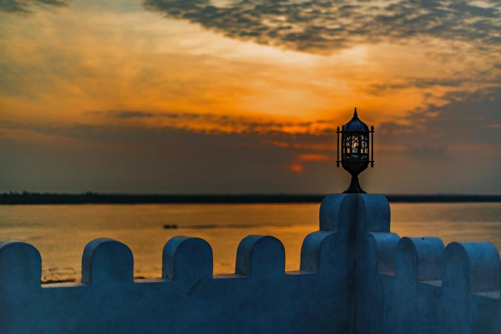 a street light on top of a fence with the sunset at Beytul Habaib in Lamu