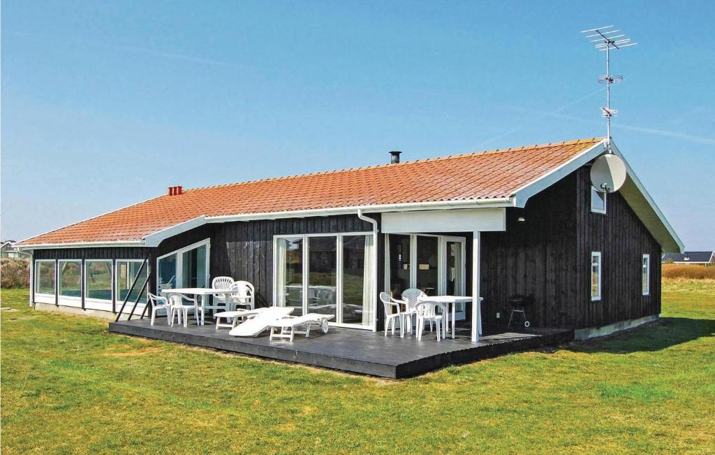 una casa con terrazza arredata con sedie e tavoli di Amazing Home In Løkken With Sauna a Løkken