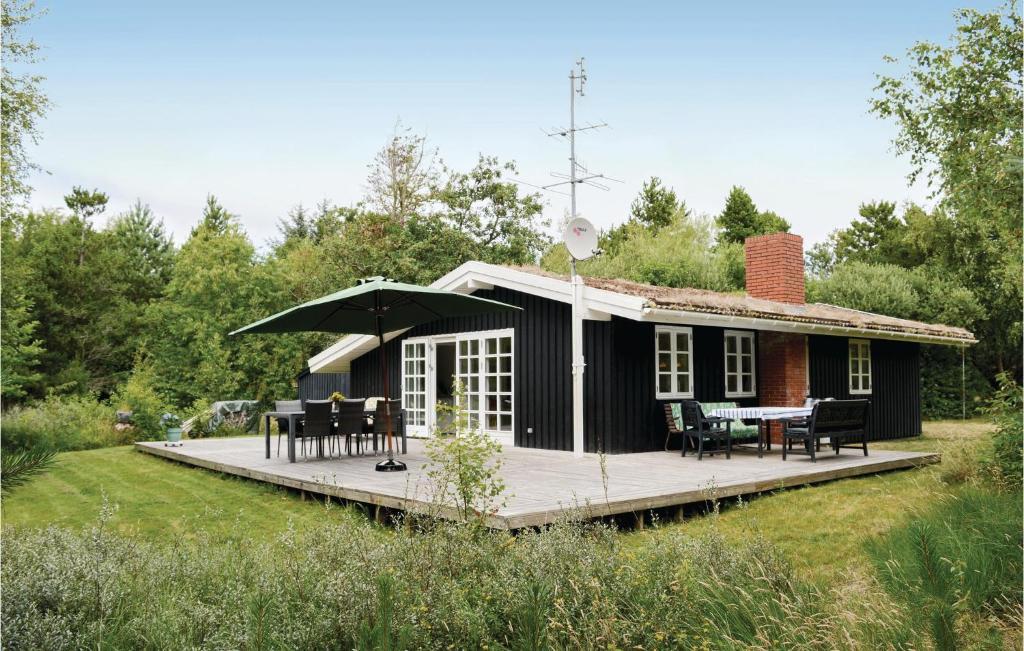 a black cottage with a deck and a table at Lovely Home In Rm With Wifi in Bolilmark